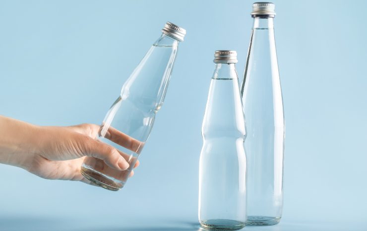 mano con bottiglie di vetro acqua