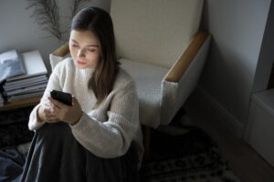 Ragazza sola al buio che guarda lo smartphone